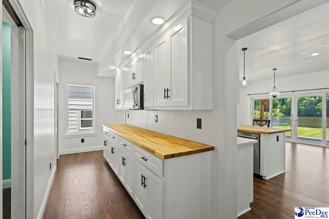 kitchen featuring wood counters, stainless steel appliances, a center island, and white cabinets