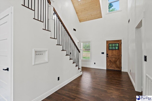 foyer entrance featuring dark wood-type flooring, a towering ceiling, and wood ceiling