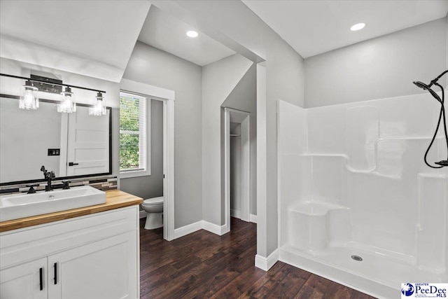 bathroom with walk in shower, vanity, toilet, and hardwood / wood-style floors