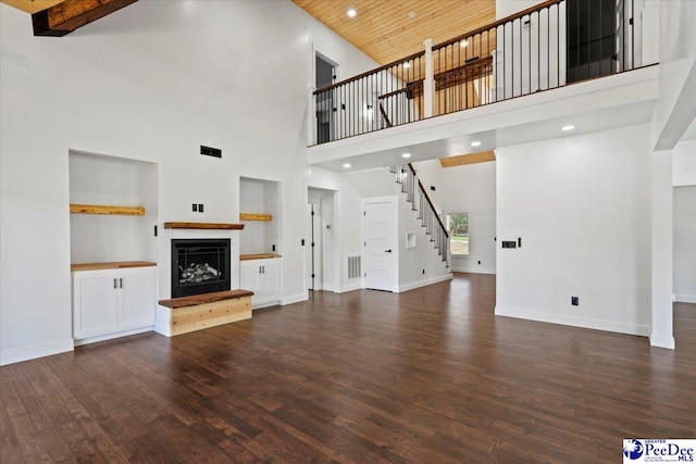 unfurnished living room featuring dark hardwood / wood-style flooring, a towering ceiling, and wooden ceiling