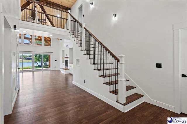 stairway featuring a towering ceiling and wood-type flooring