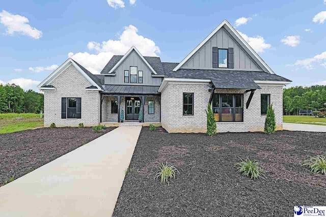 modern inspired farmhouse with roof with shingles, a standing seam roof, a porch, board and batten siding, and brick siding