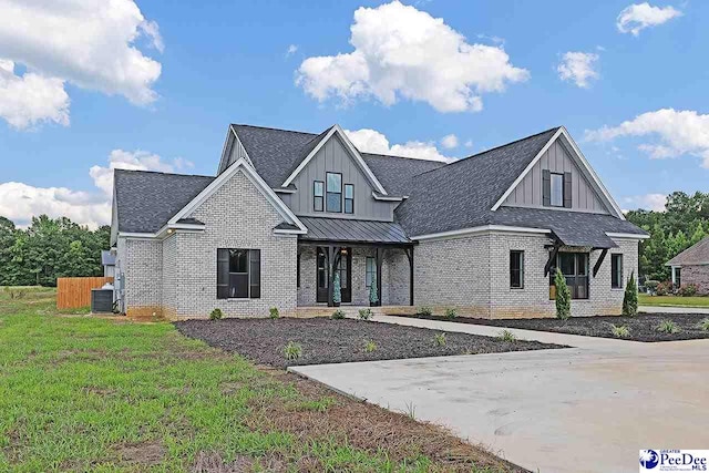 modern inspired farmhouse with brick siding, board and batten siding, a front yard, a standing seam roof, and metal roof