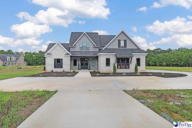 modern inspired farmhouse featuring metal roof, brick siding, roof with shingles, board and batten siding, and a standing seam roof