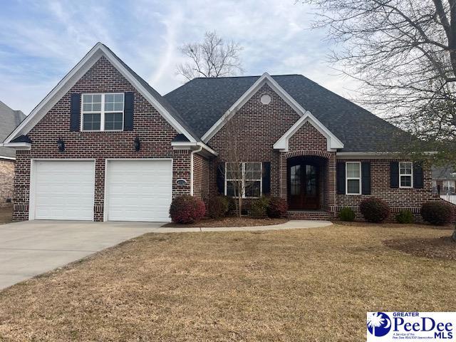 view of front of house with a front lawn, french doors, concrete driveway, a garage, and brick siding