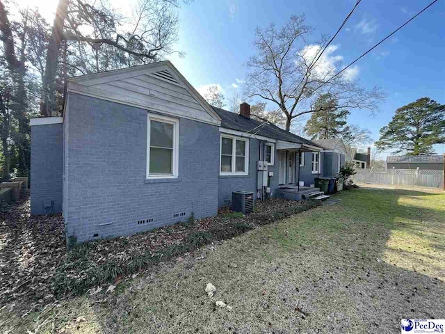 view of property exterior with central AC and a lawn