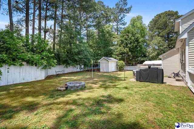 view of yard with an outdoor fire pit, an outbuilding, a shed, and a fenced backyard
