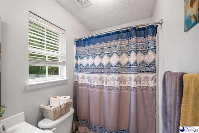 full bath featuring toilet, visible vents, a textured ceiling, and a shower with shower curtain