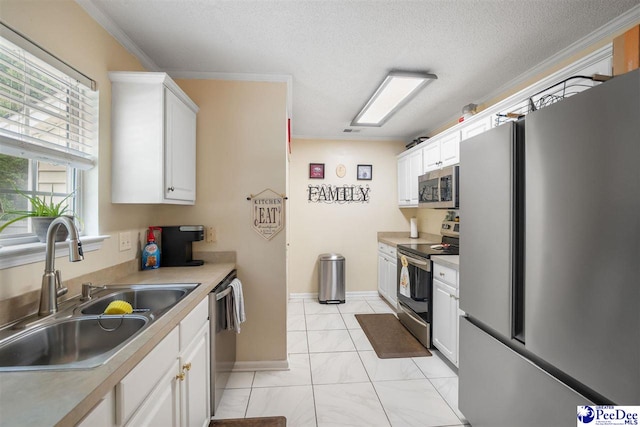 kitchen with a sink, ornamental molding, light countertops, white cabinets, and appliances with stainless steel finishes