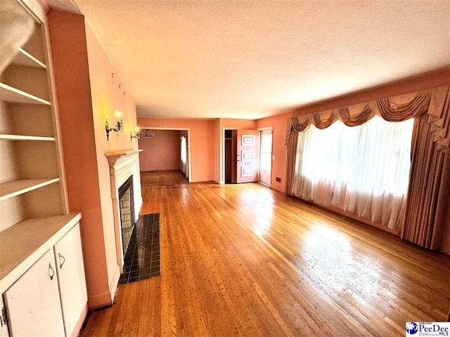 unfurnished living room with a textured ceiling, a fireplace, and wood finished floors