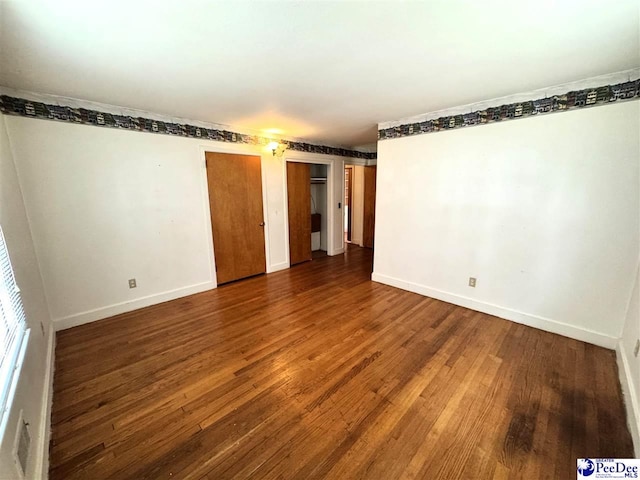 unfurnished room with dark wood-style flooring and baseboards