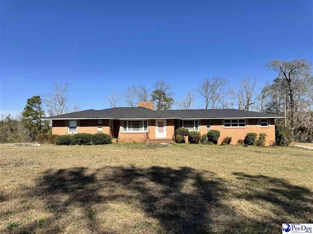 ranch-style house with a front yard, brick siding, and a chimney