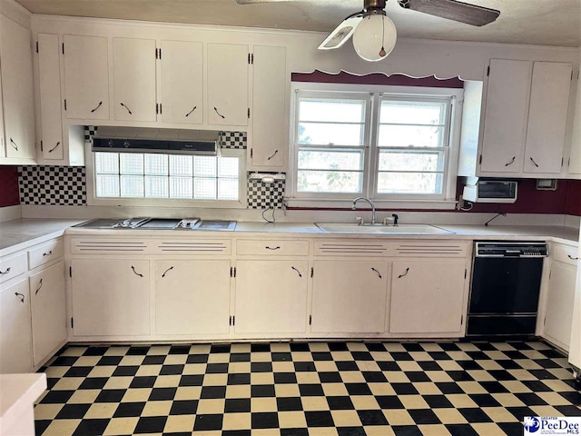 kitchen with dark floors, black dishwasher, light countertops, and a sink