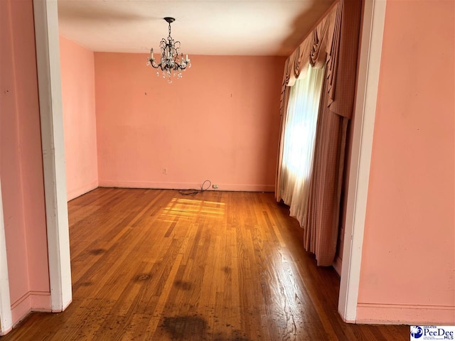 unfurnished dining area with a chandelier, light wood-type flooring, and baseboards