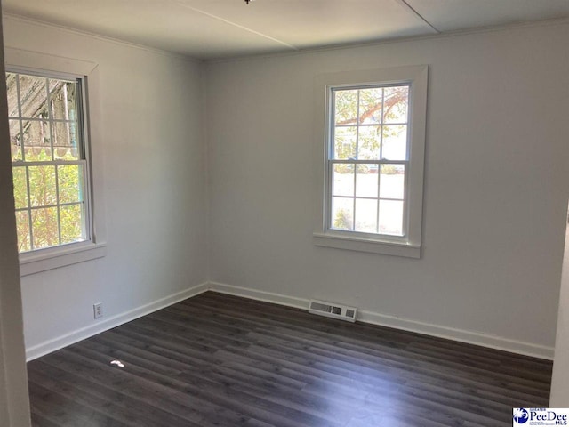 unfurnished room featuring visible vents, baseboards, dark wood-type flooring, and ornamental molding