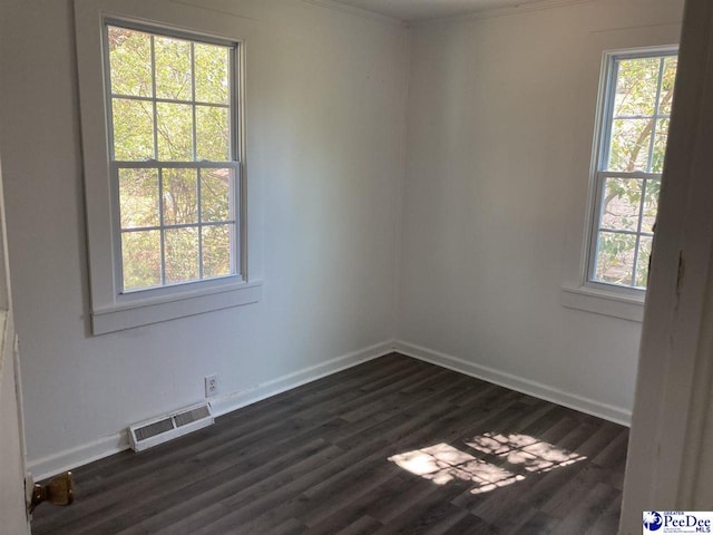 empty room with dark wood finished floors, visible vents, a healthy amount of sunlight, and baseboards