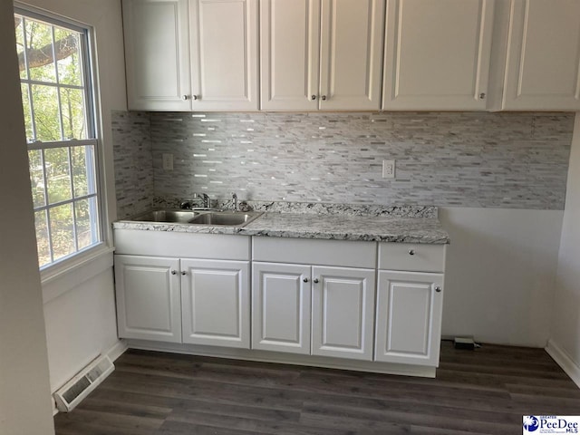 interior space with a sink, visible vents, tasteful backsplash, and dark wood-type flooring