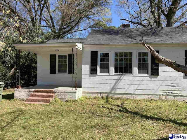 view of front of property with a front yard and a shingled roof