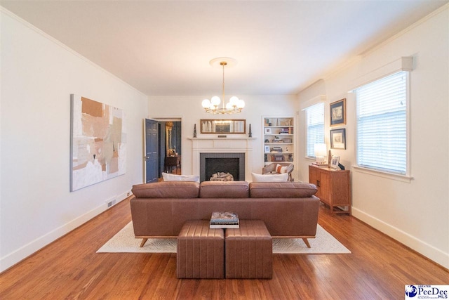 living room with an inviting chandelier, wood-type flooring, and ornamental molding
