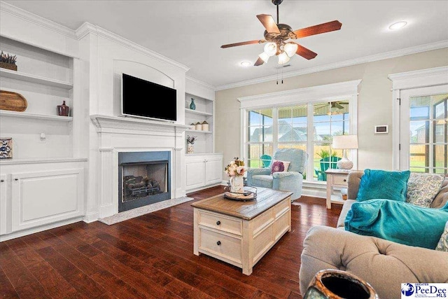 3106 Wainwright Ct, Florence, SC 29501 - living area featuring dark wood-style floors, a ceiling fan, ornamental molding, a fireplace with flush hearth, and built in shelves