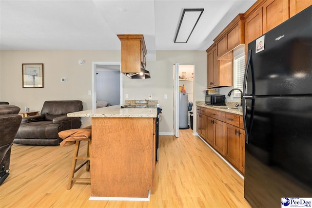 2963 Miss Annie Ct, Gresham, SC 29544 - kitchen with open floor plan, a breakfast bar area, light stone counters, light wood finished floors, and black appliances