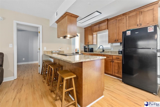 2963 Miss Annie Ct, Gresham, SC 29544 - kitchen with freestanding refrigerator, light stone counters, light wood-style flooring, and a breakfast bar area