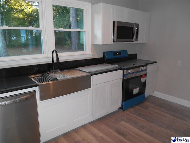 kitchen with dark hardwood / wood-style flooring, sink, stainless steel appliances, and white cabinets