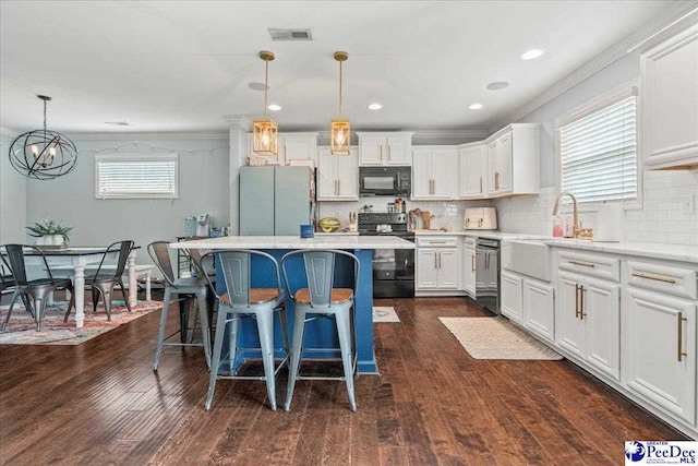 1200 Turtle Dove Dr, Effingham, SC 29541 - kitchen with black appliances, a kitchen island, a breakfast bar area, light countertops, and white cabinets