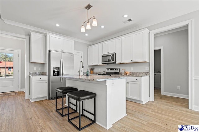 kitchen with light wood-style flooring, stainless steel appliances, hanging light fixtures, white cabinetry, and a kitchen breakfast bar