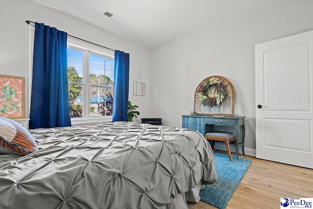 bedroom featuring visible vents, baseboards, and wood finished floors