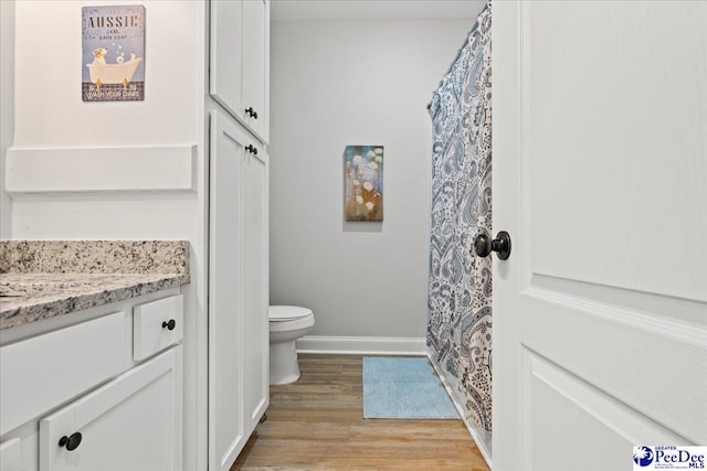 full bath with toilet, vanity, baseboards, and wood finished floors