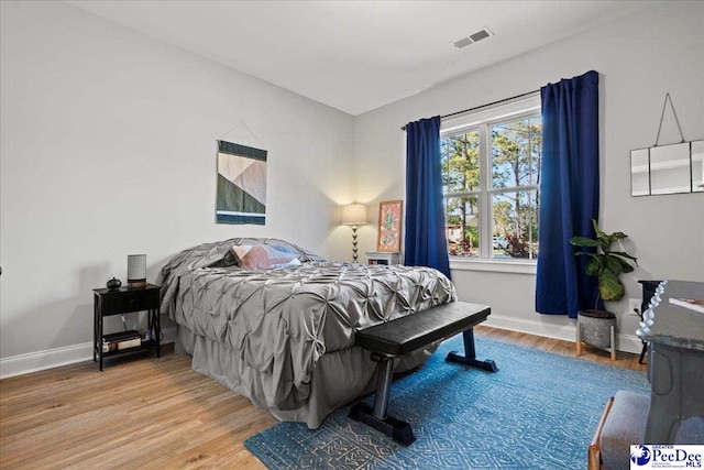 bedroom featuring visible vents, baseboards, and wood finished floors