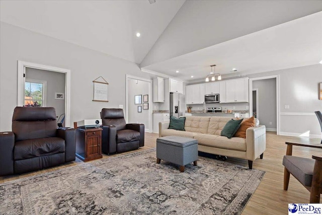 living room with recessed lighting, light wood-style floors, baseboards, and high vaulted ceiling