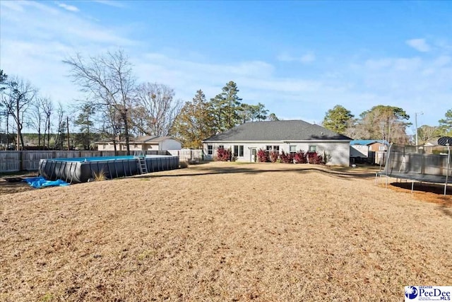 view of yard with a fenced in pool, a trampoline, and fence