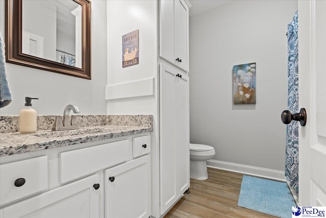 full bathroom featuring vanity, toilet, wood finished floors, and baseboards