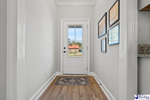 doorway to outside with plenty of natural light, crown molding, baseboards, and wood finished floors