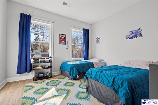 bedroom with wood finished floors, visible vents, and baseboards