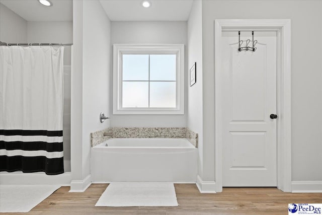 full bathroom featuring recessed lighting, baseboards, a garden tub, and wood finished floors
