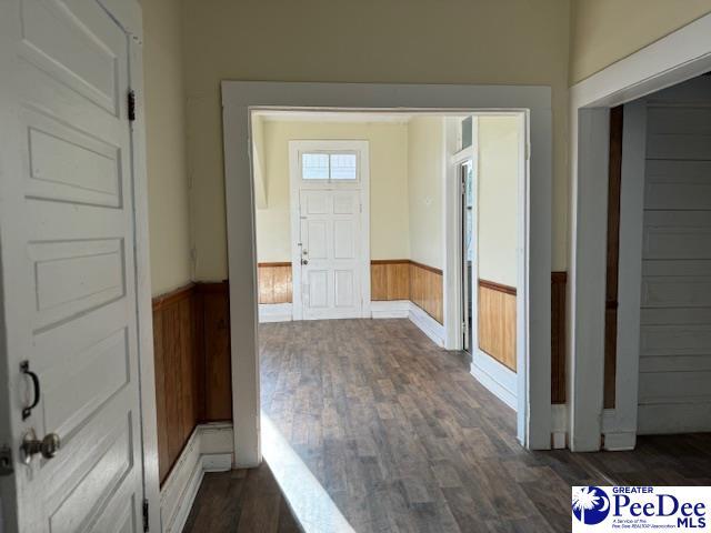 interior space with dark hardwood / wood-style flooring and wooden walls