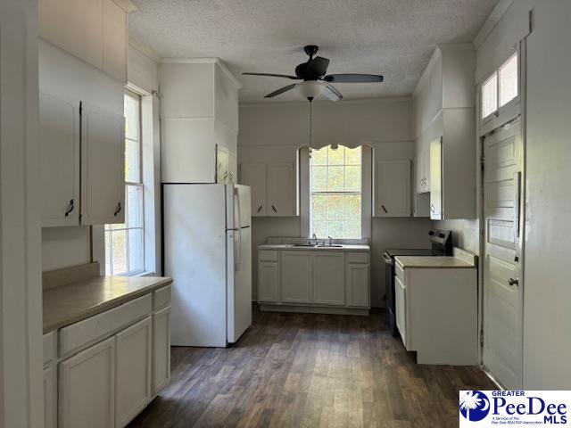 kitchen featuring stainless steel range with electric cooktop, a textured ceiling, white refrigerator, dark hardwood / wood-style floors, and white cabinets