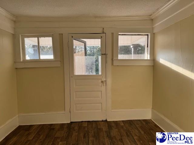 doorway to outside featuring ornamental molding, dark hardwood / wood-style floors, and a textured ceiling