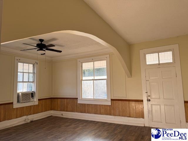 entrance foyer featuring lofted ceiling, ceiling fan, cooling unit, wood-type flooring, and wood walls