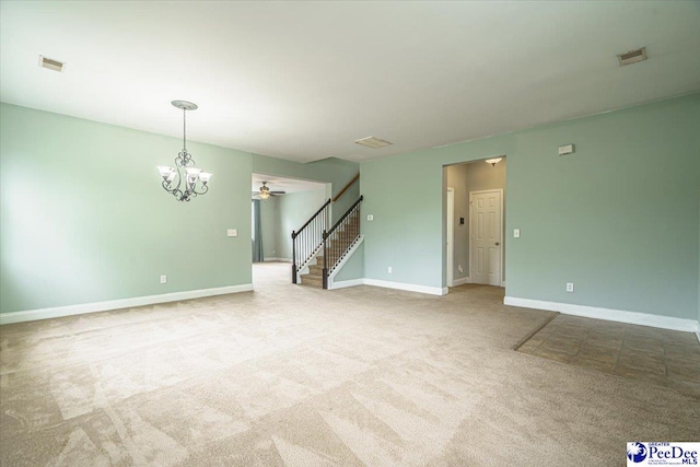 carpeted empty room featuring ceiling fan with notable chandelier