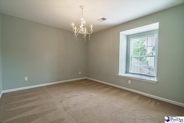 empty room featuring a chandelier and carpet floors