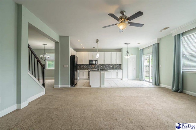 unfurnished living room featuring light carpet and ceiling fan with notable chandelier