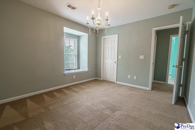 unfurnished room with carpet flooring and a notable chandelier