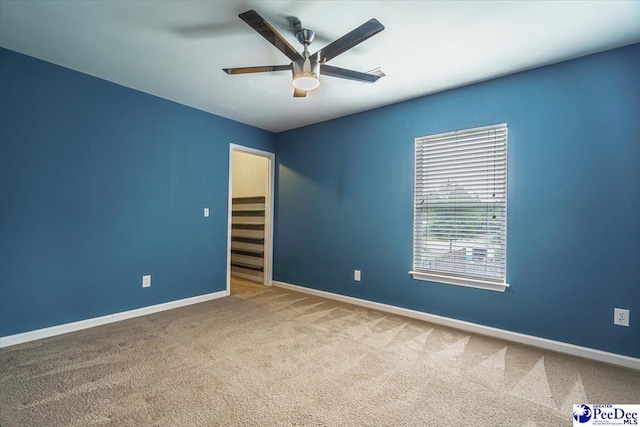 carpeted spare room featuring ceiling fan