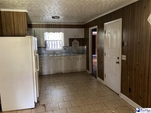 kitchen featuring white refrigerator, crown molding, sink, and white cabinets