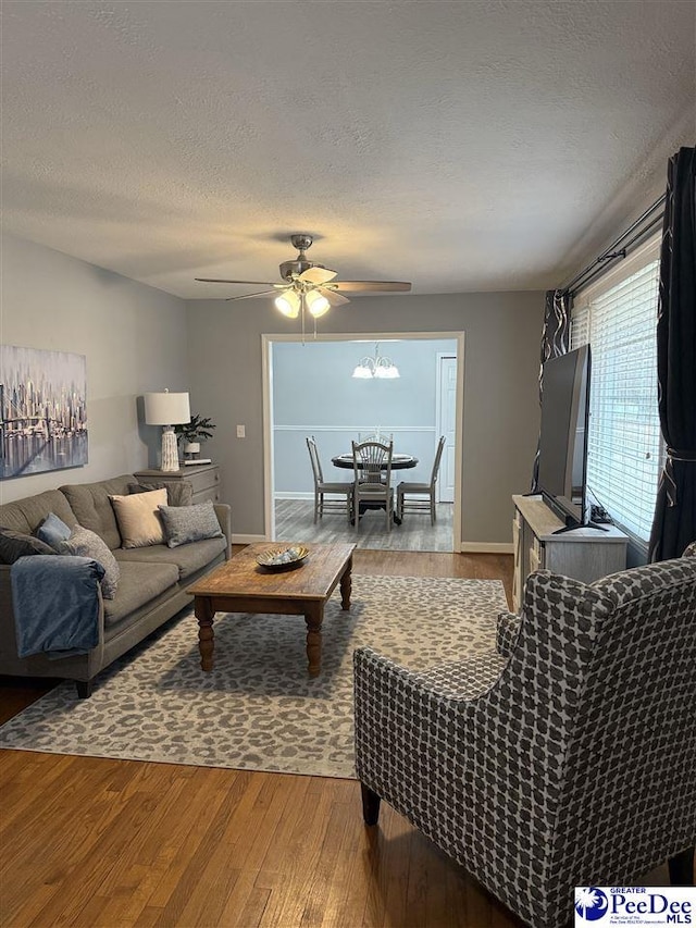 living room featuring ceiling fan, hardwood / wood-style floors, and a textured ceiling