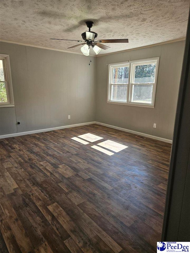 unfurnished room with dark wood finished floors, plenty of natural light, baseboards, and a textured ceiling